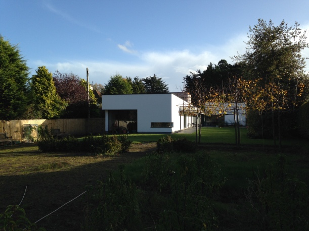 Long view down the large unplanted back garden towards the contemporary house
